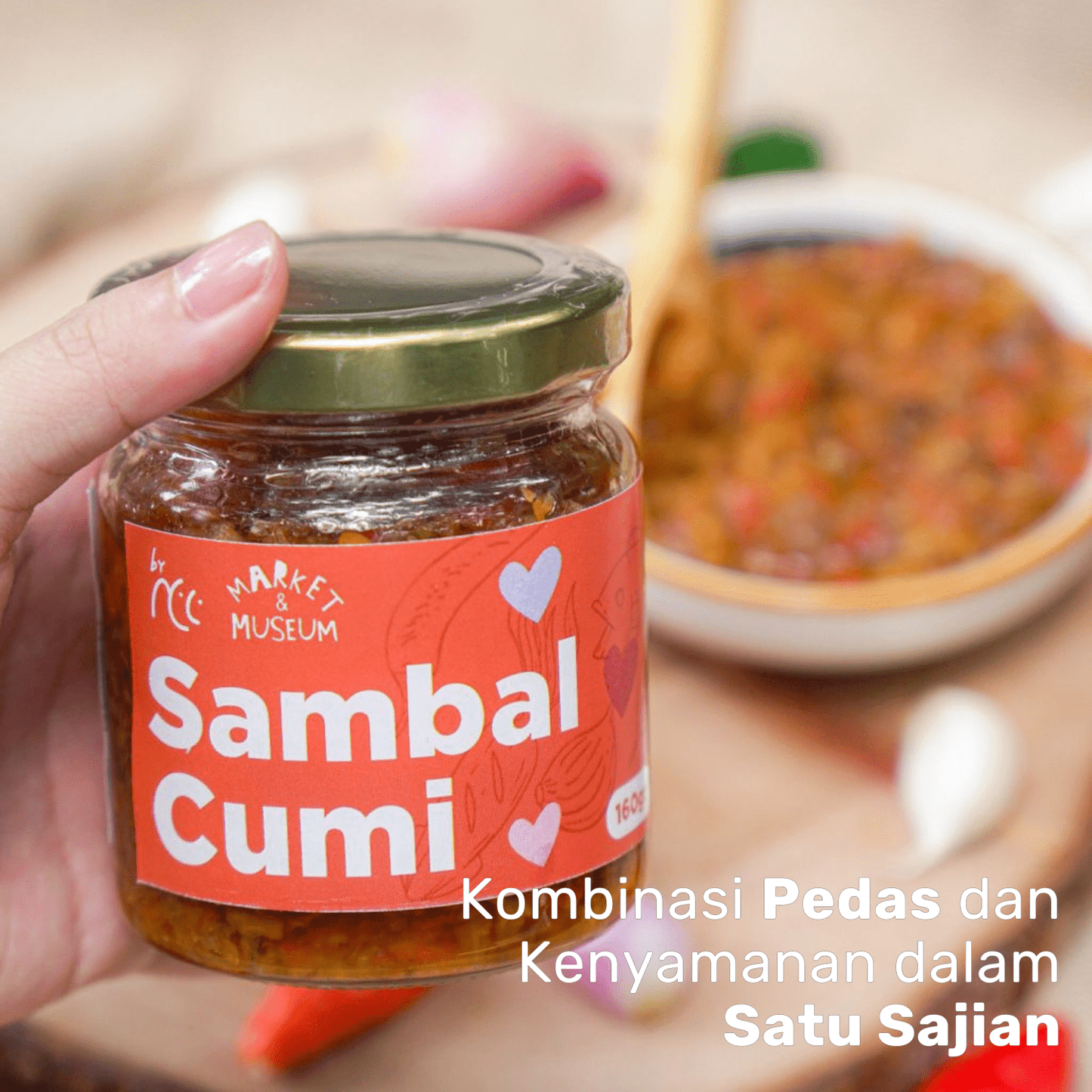 Jar of By NCC Sambal Cumi Pedas Gurih Rumahan spicy savory squid chili sauce with bowl of sauce in background